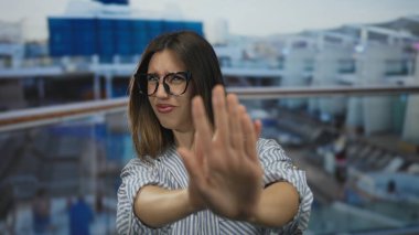 Çizgili tişörtlü genç İspanyol kadın yolcu güvertesinde el kaldırarak jest yapıyor, reddediliyor..