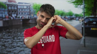 Kanal caddesinde elleri ile kalp hareketi yapan kırmızı tişört giyen genç İspanyol cankurtaran..