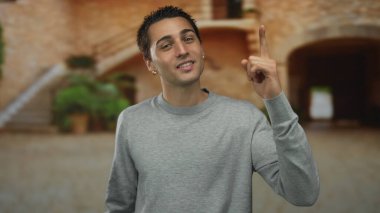 Genç bir adam, eski bir kasabada, manzaranın tadını çıkarırken, güzel bir jest sergiliyor..