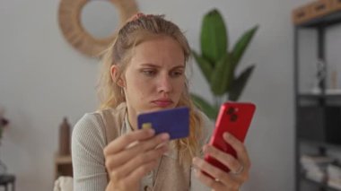 Kadın evde ödemesini yaparken akıllı telefonu tutuyor. Sarışın, genç ve etkileyici kadın ise kapalı bir iç mekâna odaklanmış bir kart yerleştiriyor..