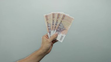 İzlanda Krona banknotları tutan adam izole edilmiş beyaz bir arkaplan karşısında, finansal başarı ve para yönetimi minimalist bir ortamda sergileniyor.