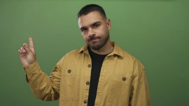 Tarafsız ifadeli sarı ceketli bir adam stüdyoda solu işaret ediyor..