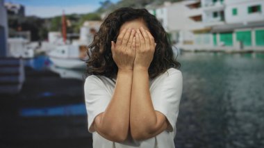 İspanyol kadın gözlüklü ve beyaz gömlekli. Deniz manzaralı bir limanda tekneler ve renkli binalarla eğleniyor ve şaşırıyor..