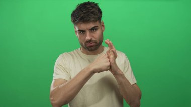 Genç İspanyol adam, basit yeşil stüdyo duvarına sıkılmış yumruğuyla yumruk atıyor. Kararlılık..