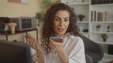Kıvırcık saçlı bir kadın akıllı telefondan suni teneffüs yapıyor..