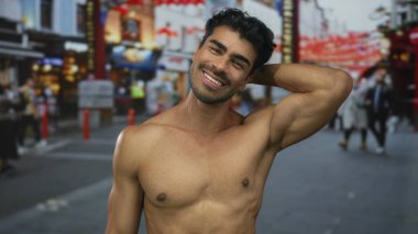 Gömleksiz genç adam elleri koyu renk saçlar arasında koşar ve caddede göğüslerinin rengini gösterir..