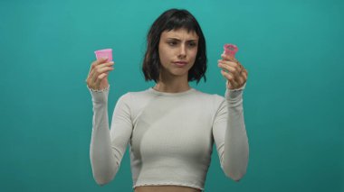 Stüdyoda iki pembe regl bardağını çıplak elle karşılaştırır; düşünsel sürdürülebilirlik.