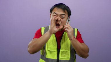 Cep telefonunda, izole edilmiş mor arka plan görüntülerine karşı çelik yelek giymiş öfkeli bir şekilde bağıran bir adam..