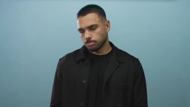 Sakallı İspanyol adam mavi stüdyoda yüzünü ve dudaklarını gösteren aşağı bakar; melankolik yansıma şüphe.