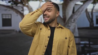 Kalabalık bir caddede beyaz binanın önünde alından alnına gülümseyen bir adam; rahatlama, huzur..