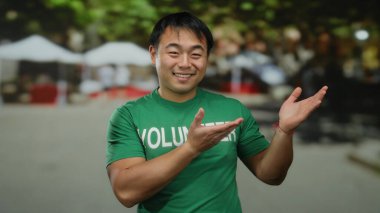 Sokak ortamında yeşil gönüllü gömleği içinde gülümseyen genç adam, olumlu hayır işleri yapıyor..