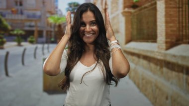 Kadın elleri ile çerçeve ve tuğla bina yanında gülümseme görünür bilezikler; keyif güven oyun.