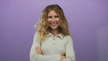 Stüdyoda kollarını kavuşturarak poz veren bir kadın mor portre içinde genç ve güzel bir gülümseme yayıyor..