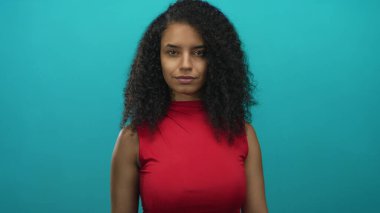 Stüdyoda kırmızı bluz giyen İspanyol kadın pazılarını esnetiyor; güven güçlendirme kararlılığı.