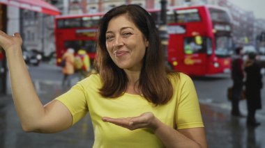 Meşgul caddede avuçlarında jest ile gülümseyen orta yaşlı kadın sarı gömlek giyiyor, iyimserlik özgüveni.