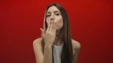 Genç İspanyol bir kadın canlı kırmızı bir stüdyo arkaplanına el pençe dize öpüşüyor..