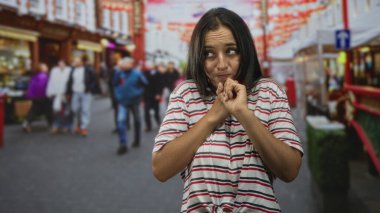 Meşgul bir şehir caddesinde göğsüne yakın el ele tutuşan genç İspanyol kadın; sinir bozucu belirsizlik..