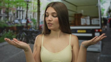 Kafkasyalı genç kız sorgu jesti için elini kaldırdı; belirsizlik kafa karışıklığı şüphesi.