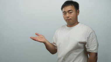 Genç Çinli adam açık mavi stüdyoda avuçiçi sunar; özgüven hırsı fırsat yeniliği.