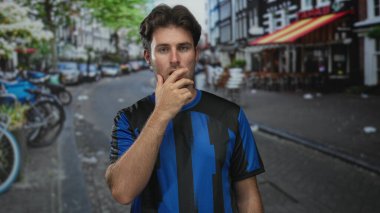 Sokak kafede parmakları dudaklarına kadar uzanan mavi formalı bir adam park etmiş bisikletli, elden ağıza yakın, sessiz bir iç gözlem..