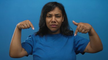 Kadınlar mavi stüdyoda parmaklarını aşağı doğru gösteriyor sert bir ifadeyle ve daralmış gözleriyle; onaylanmamış uyarı.