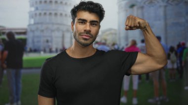 Genç İspanyol adam, yumruğunu sıkarak kol kaslarını esnetiyor ve sidik kulesi binasına hafifçe gülümsüyor..