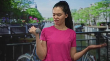 Güneşli bir sabah antrenmanı sırasında Amsterdam 'da sokak köprüsünde esnek kollu gri halteri tutan kadın, kararlılık.
