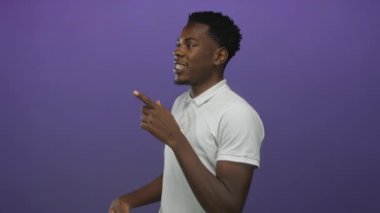 Stüdyoda gülümseyen ve işaret eden bir adam mor arka planda oyuncu bir işaret hareketi sergiliyor..
