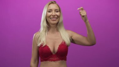 Stüdyoda kırmızı dantelli sutyen giyen sarışın bir kadın, iyimserlik özgüveni yüksek..