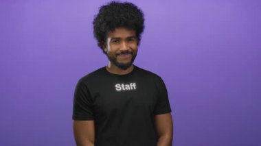 Üniformalı Afrikalı Amerikalı adam, izole edilmiş mor arka plana karşı işaret ediyor.