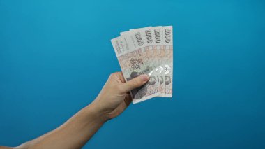 Beyaz adamın eli İzlanda Krona banknotlarını canlı, mavi bir arkaplanda tutuyor..