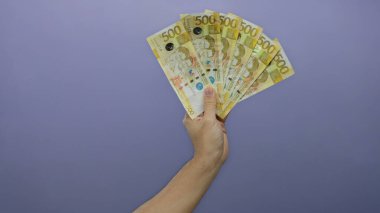 Mor bir arkaplan karşısında Filipinli pezoları tutan erkek el ele tutuşma, izole bir ortamda parasal zenginlik ve finansal konsepti gösteren bir banknot hayranı sergiliyor.