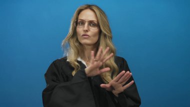 Bir kadın stüdyoda mavi arka planda üniforma giyen genç sarışın bir yargıçla konuşurken el ele tutuşuyor..