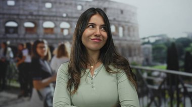 Roma Kolezyumu 'nun dışında neşeli bir tavırla gülümseyen bir kadın. Roma' daki ikonik antik siteyi keşfeden, seyahat ve tarih gösteren neşeli bir kalabalık arasında..