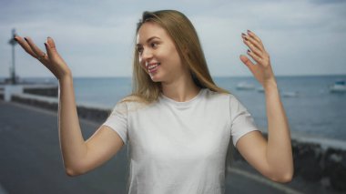 Sahilde sırıtan bir kadın, arka planda suyla birlikte keyifli bir günde açık deniz manzarasının keyfini çıkarıyor..