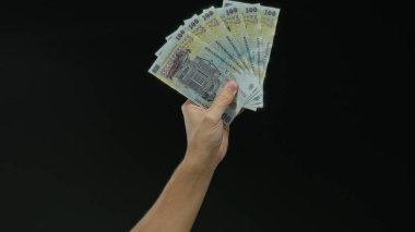 Romen banknotlarını elinde tutan beyaz adam, kara izole edilmiş bir geçmişe karşı, para, finans, ticaret, zenginlik, para, bankacılık, ekonomi ve nakit kavramlarını gözler önüne seriyor.