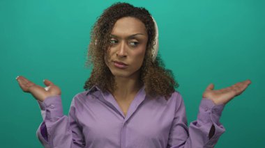 Mor gömlekli transseksüel kadın kulaklık takıyor ve avuçlarını yeşil bir stüdyo ortamında tutuyor..