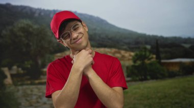 Yeşil parkta boğazını sıkan kırmızı şapkalı ve gözlüklü genç bir teslimatçı. Rahatsız edici..