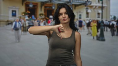 Kalabalık caddedeki gösterişli binanın dışında çıplak kadın baş parmak hareketi gösteriyor; onaylanmıyor.