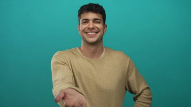 Erkek genç İspanyol deniz mavisi portresinin altında poz verirken erkek elini stüdyo arkaplanından seyirciye uzatıyor..