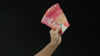 Filipinli pezolarla el ele tutuşan, siyah arka planda izole edilmiş, çarpıcı detaylarla göze çarpan para birimi..