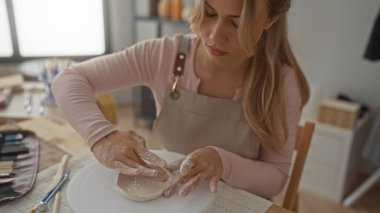 Seramik stüdyosunda çömlek çarkını çıplak elle şekillendiren kadın; yaratıcılık odaklı sükunet.