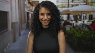 Canlı bir sokak ortamında gülümseyen bir kadın. Bulanık bir restoranın terasında canlı bir şehir manzarası sergiliyor..