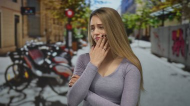 Sonbahar boyunca şehir caddesinde dikilen kadın, düşünceli ve düşünceli, arka planda bisikletlerle çevrili şehir manzarasıyla çevrili..