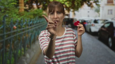Elinde küçük kırmızı keçeli kalple gezen kadın kamerayı işaret ediyor..