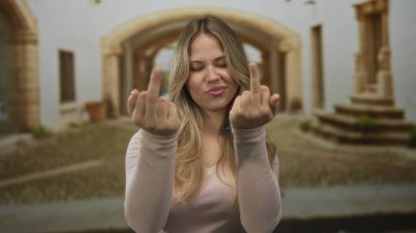 Güneşli bir günde gülümseyen genç kadın, üniversite manastırında orta parmağını kaldırır..