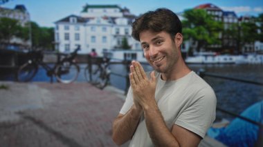 Elleri sımsıkı bağlı bir adam, Amsterdam 'da bir caddede bisiklet ve deniz kıyısındaki binalarla güler yüzlü, kendine güvenen bir adam..