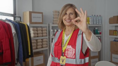 Gönüllü yelek giyen kadın elbise raflarının yanında ve raflarda el ele imza atıyor. Cömertlik onayı..