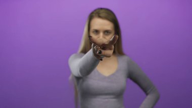 İzole edilmiş mor arka plan üzerinde ihtiyatlı hareketler yapan, genç beyaz hatlarıyla dikkat çeken, bir stüdyo ortamında odaklanmış bir görüntü yaratan bir kadın..