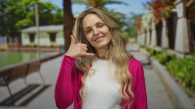 Kadın parkı işaret ediyor genç sarışın açık hava yeşil gülümseyen hırka davetkar bir an yaratıyor.